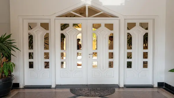 Carpenter & Sofa Repair Services Dubai, Sharjah, Ajman - Raseen Guide 2026 Carpenter repairing a wooden villa door in Dubai, with sofa reupholstery in background